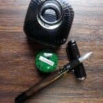 Diamine Green Black ink bottle with fountain pen and ink cap on wooden surface