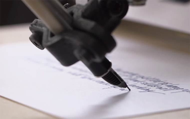 Close-up of a Bond robot hand writing with a fountain pen on white paper