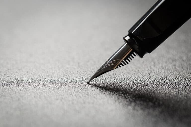 A fountain pen nib pressing on a dark surface
