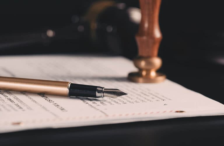 A bronze fountain pen and wax seal stamper on a legal document