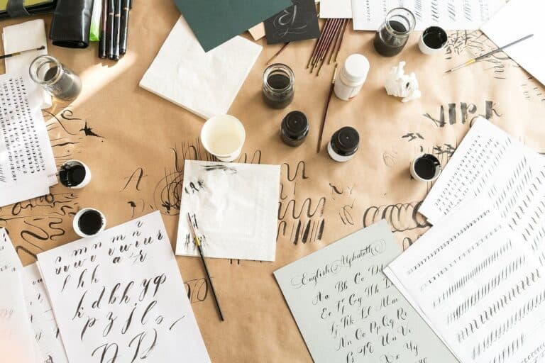 Calligraphy sheets, nibs, paper, ink and pens on a kraft background.