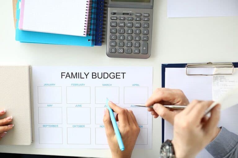 Family budget planning with calculator, notebooks, and hands writing on paper