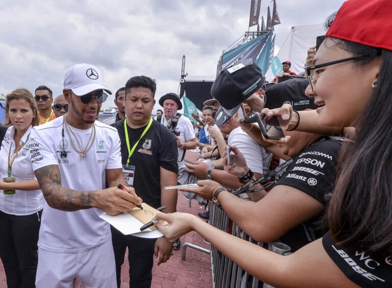 Formula One's Lewis Hamilton signing a book for a fan