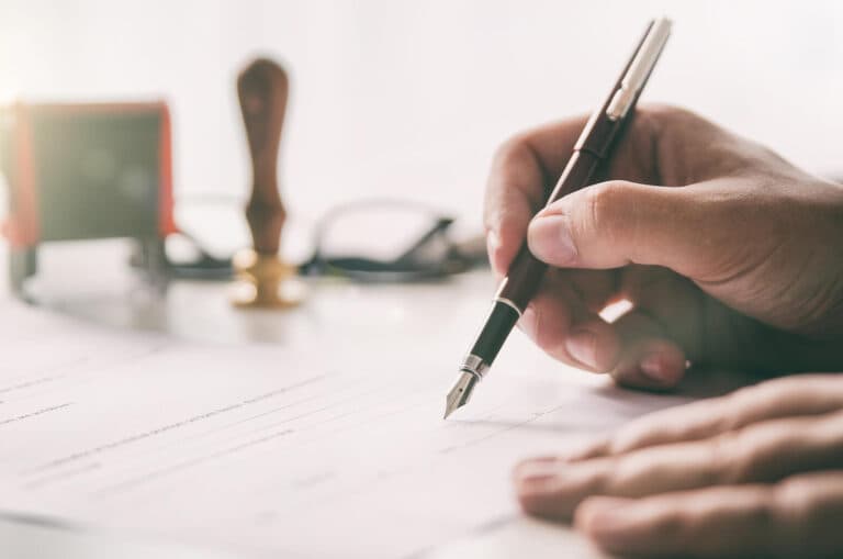 Close-up of a hand holding a fountain pen on a legal desk.