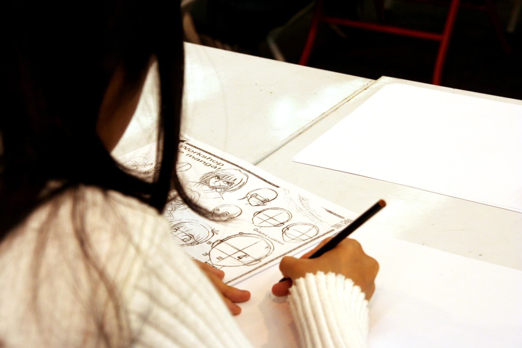 A girl or woman sat drawing manga