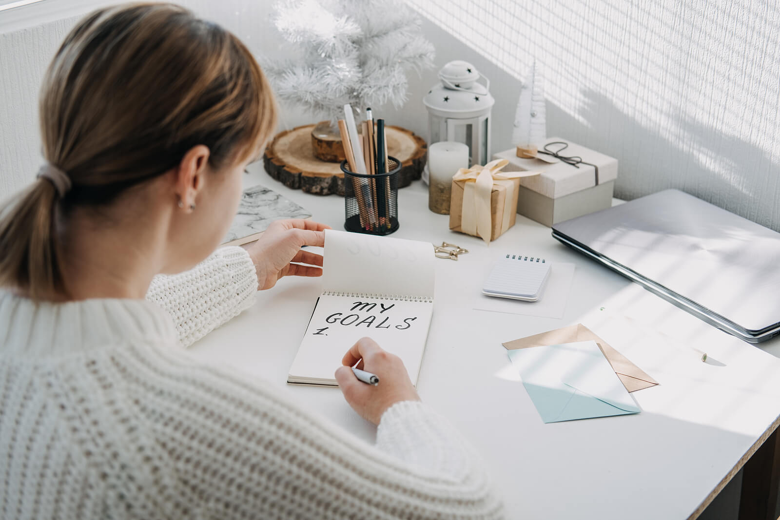A woman sat at her desk, writing her New Year's resolutions by hand.