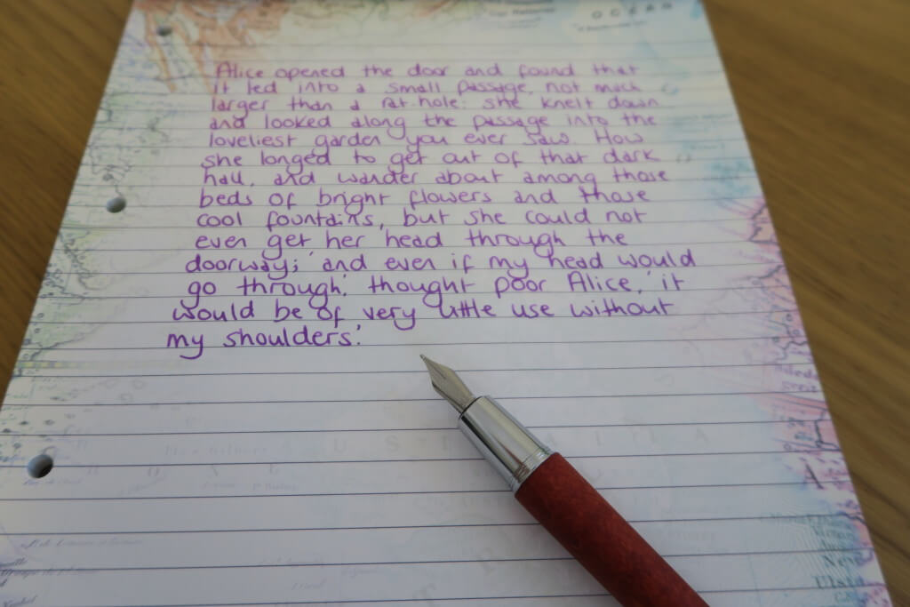 The Faber-Castell E-Motion pear wood fountain pen in brown, with handwriting example in purple Delta ink