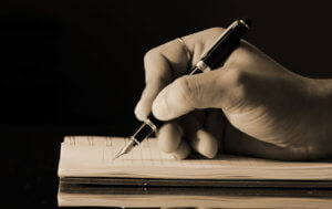 A hand writing with a fountain pen into a book.