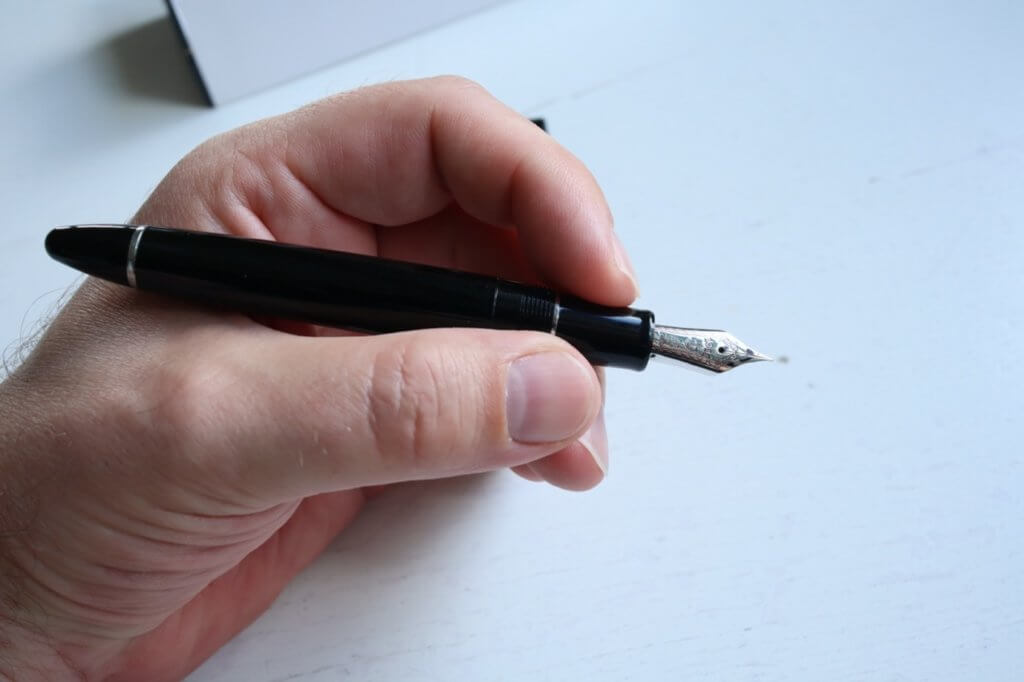 An unposted Sailor 1911 Ringless fountain pen in Simply Black, being held in a hand
