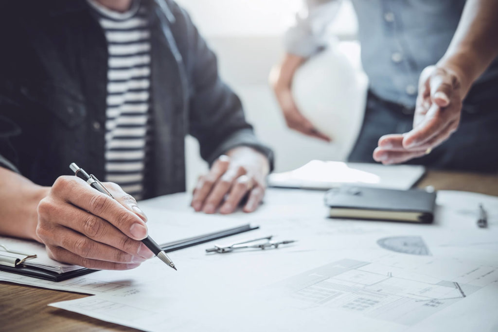 An architect or engineer completing a technical drawing with a mechanical pencil.