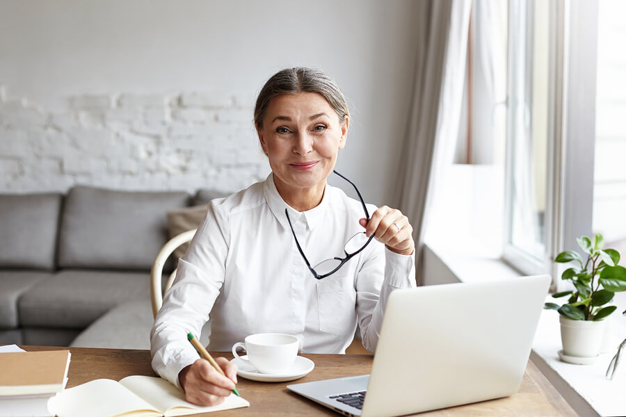 Woman writing a book on her laptop and notepad