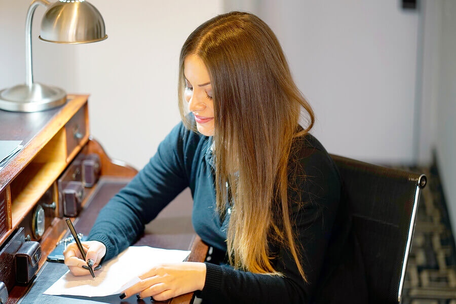 woman writing letter sat at desk