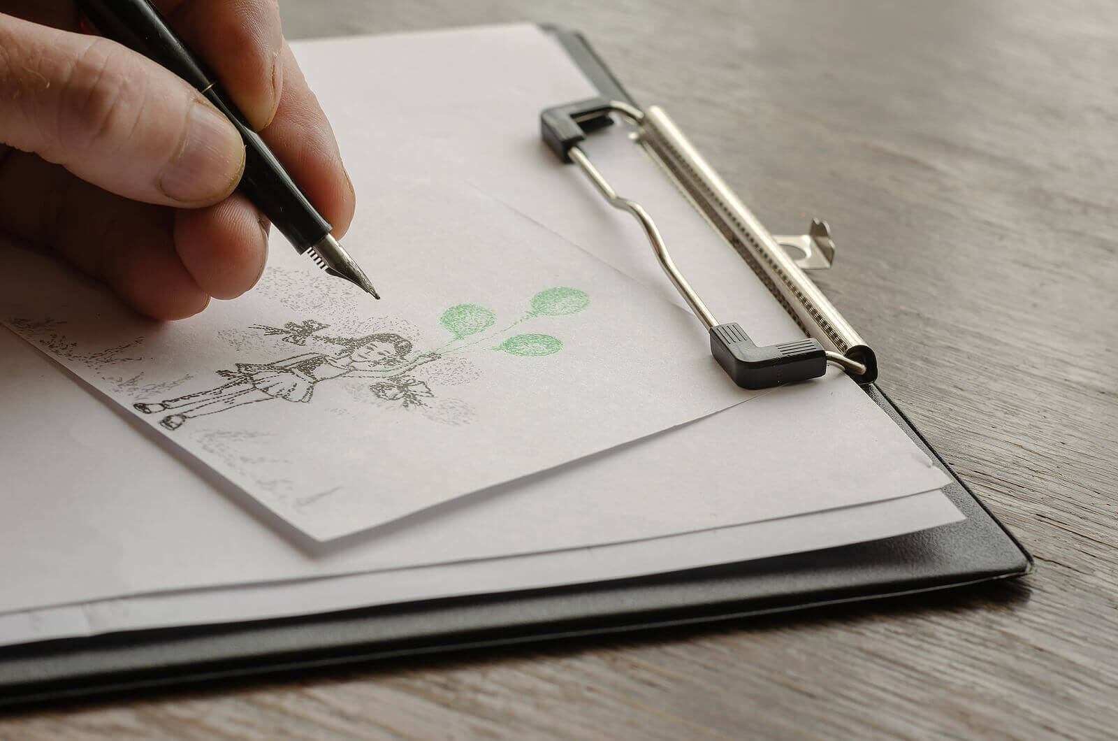 Save Download Preview An adult male hand draws a girl with green balloons on paper.