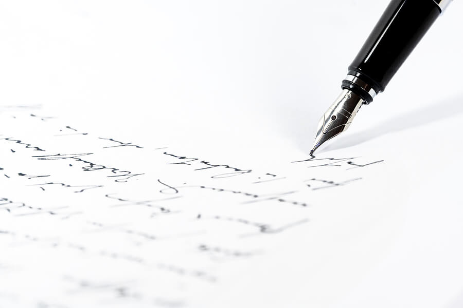 Black fountain pen is writing a letter or a manuscript on a white paper