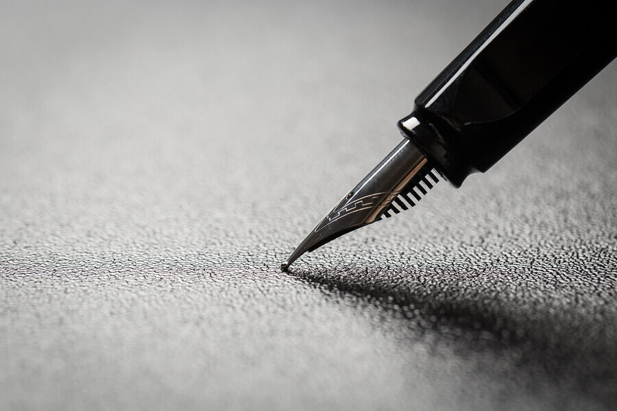 A fountain pen nib pressing on a dark surface