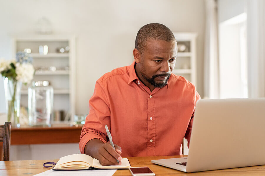 a man writing a story using his laptop and notepad