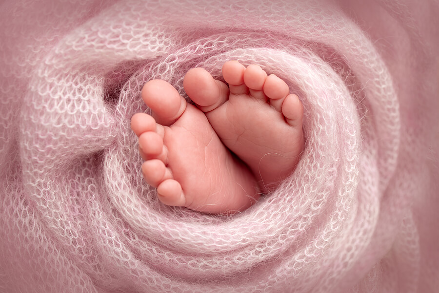 Soft feet of a newborn in a pink woolen blanket. Close-up of toes, heels and feet of a newborn baby.The tiny foot of a newborn
