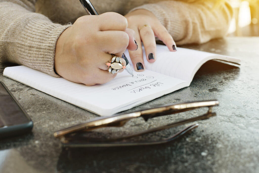 Teen hands writing in a journal