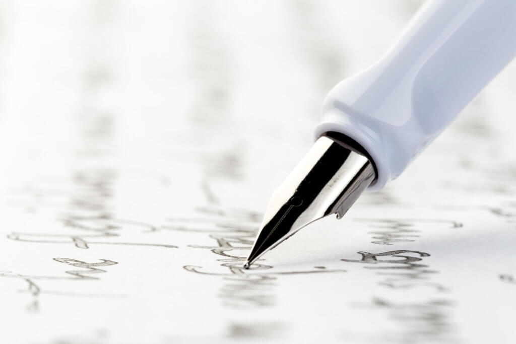 a white fountain pen writing on paper
