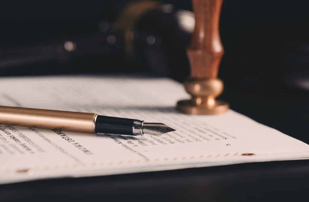 A bronze fountain pen and wax seal stamper on a legal document