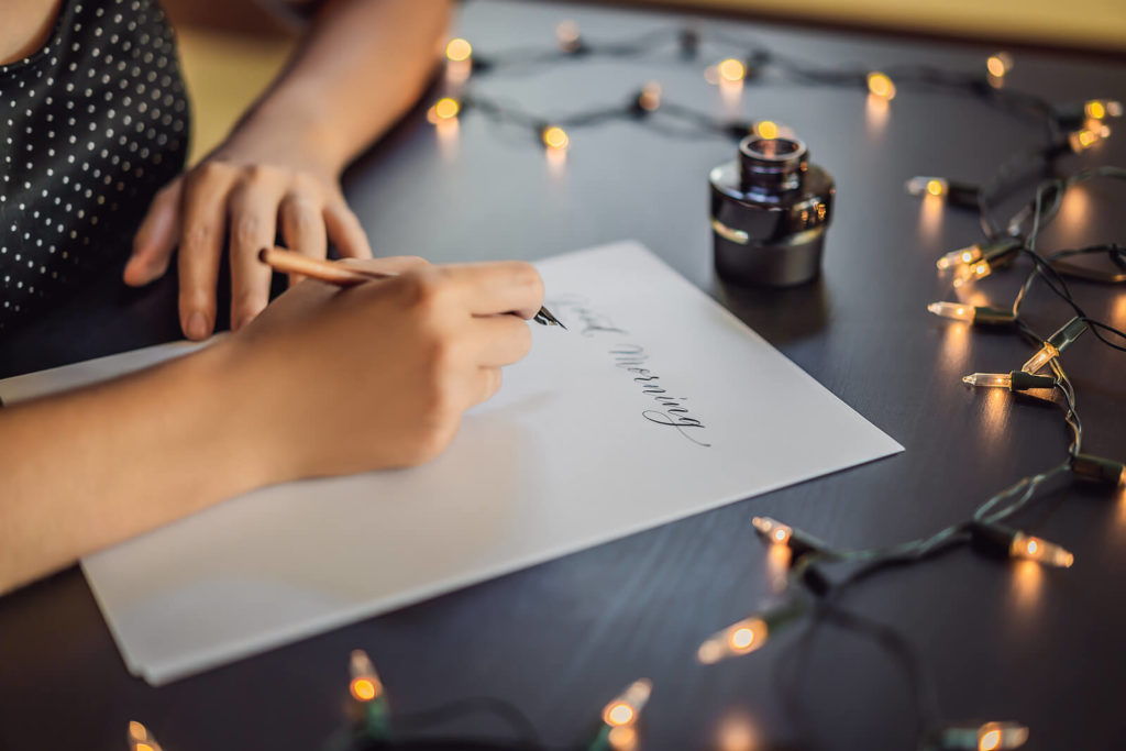 A calligrapher creating calligraphy with a dip pen and ink
