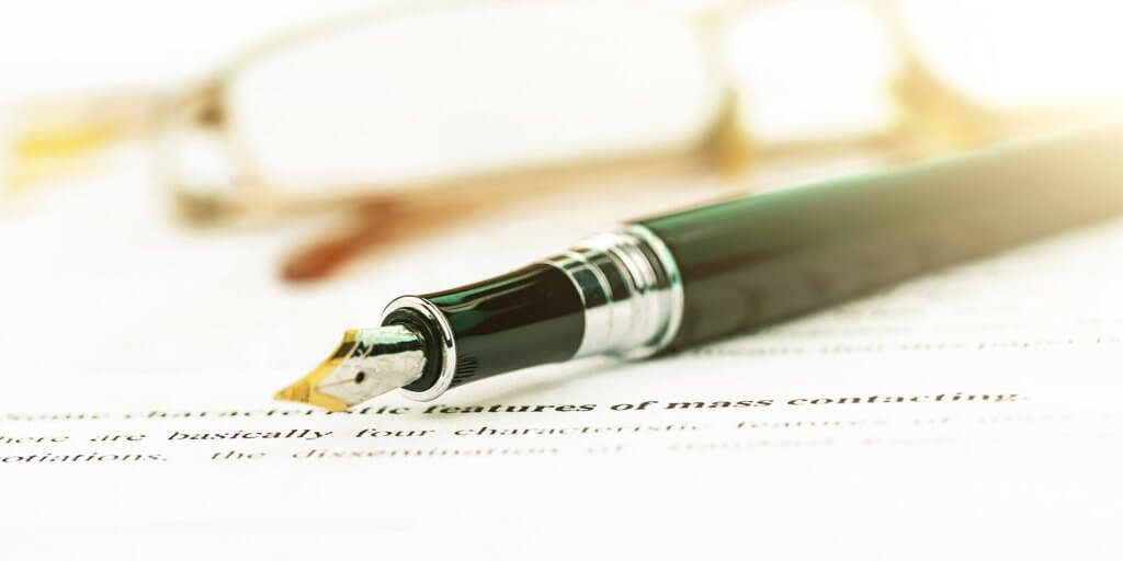 A fountain pen layed on a piece of paper with some writing on.