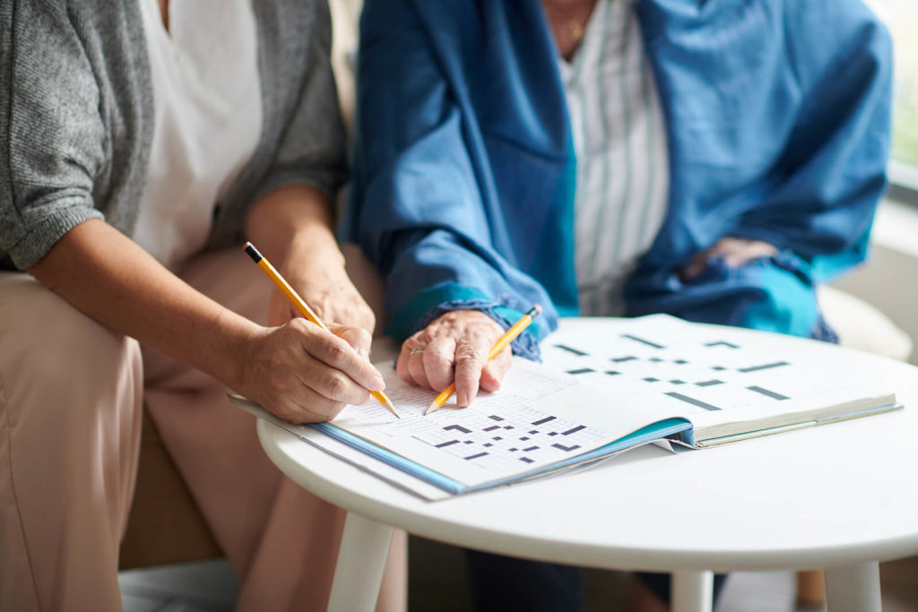 A close-up focused on hands of two people solving a crossword together.