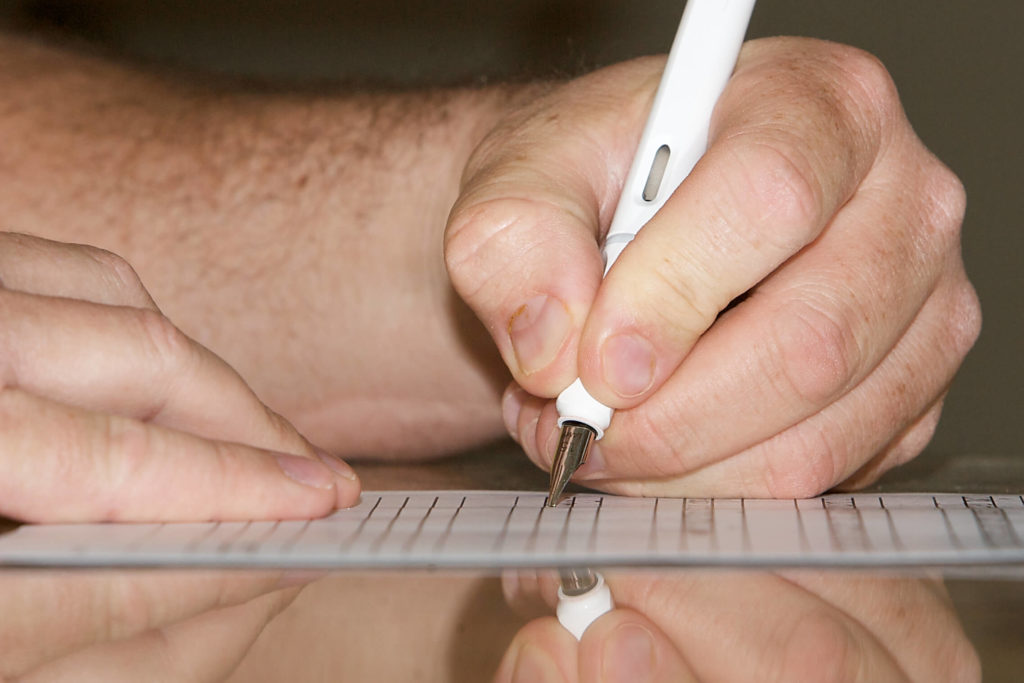 A close-up of someone writing with a fountain pen in their left hand.