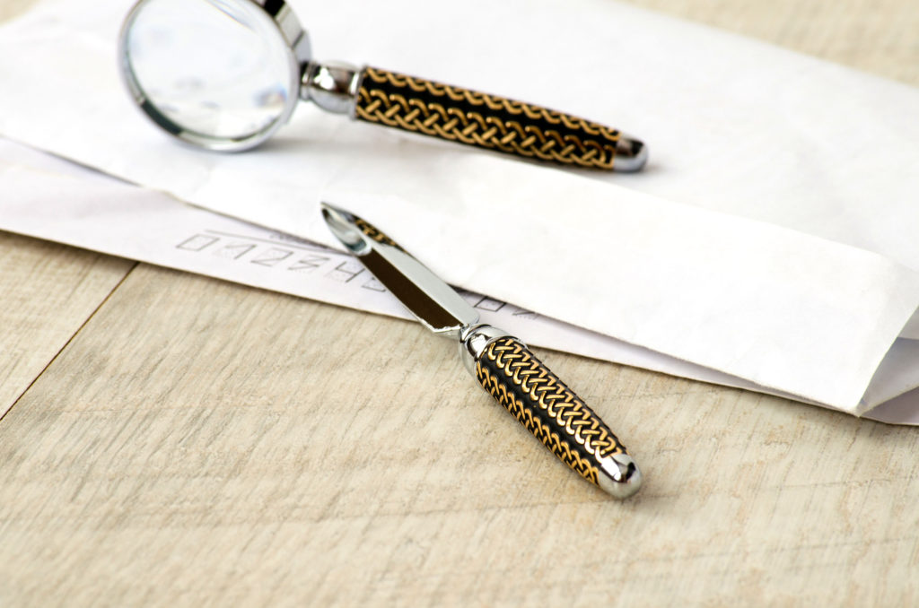 Stationery — a magnifying glass, paper knife, and letter on the wooden table.