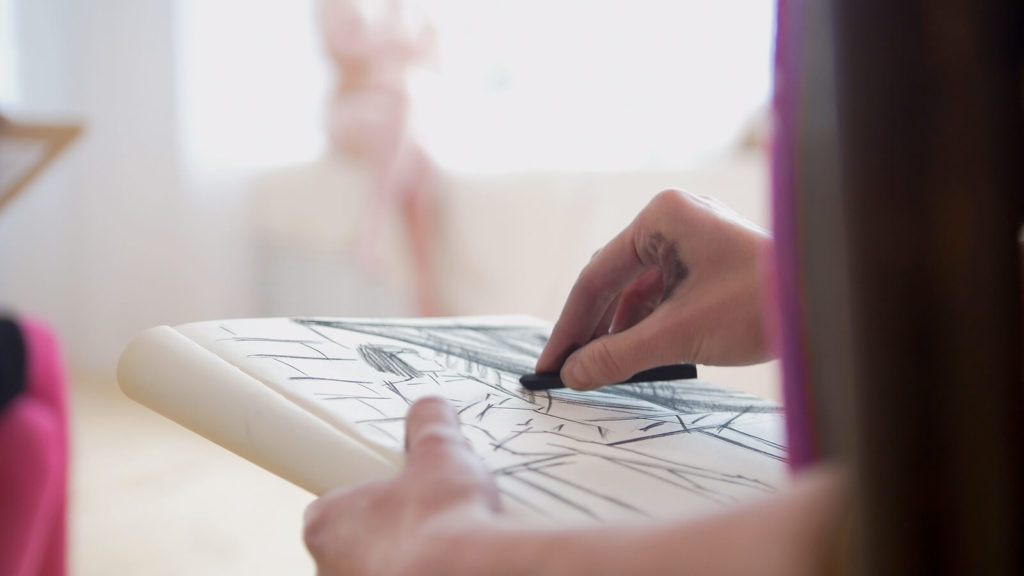 Close-up shot of someone drawing a nude model in a life drawing class.