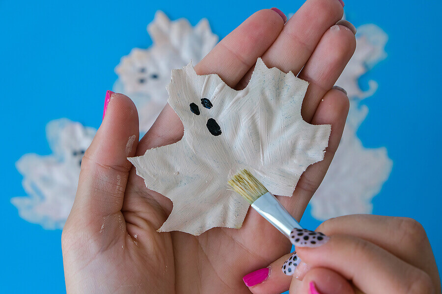 A maple leaf painted to look like a white ghost for Halloween