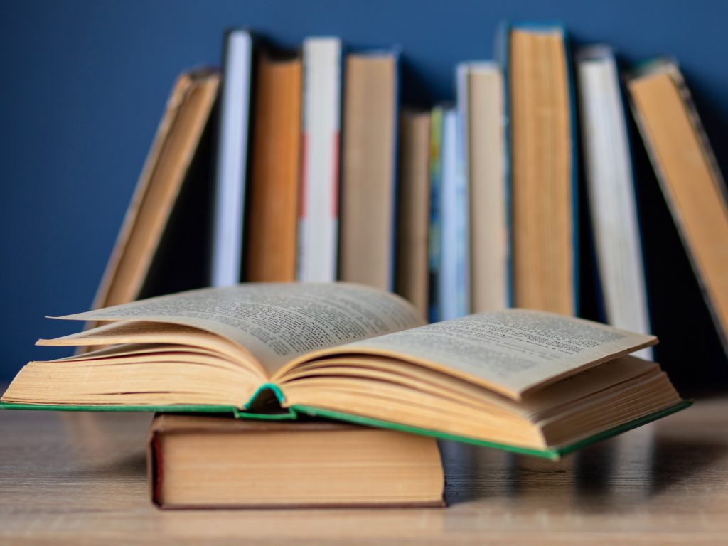 An open book and a stack of books to read.