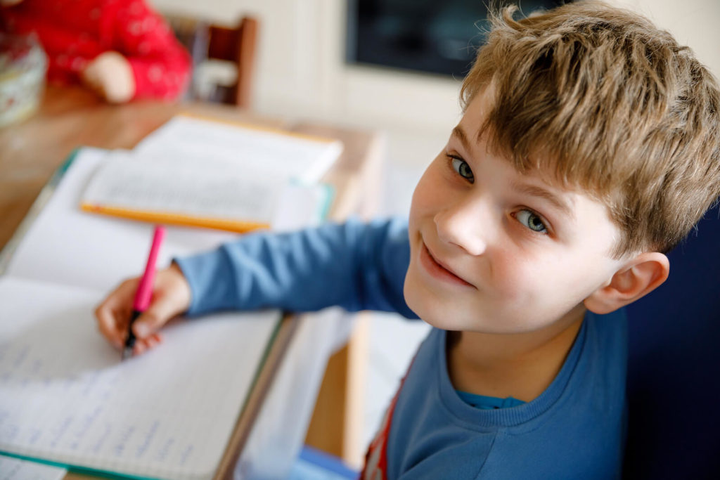 A boy using a fountain pen to complete his school homework.