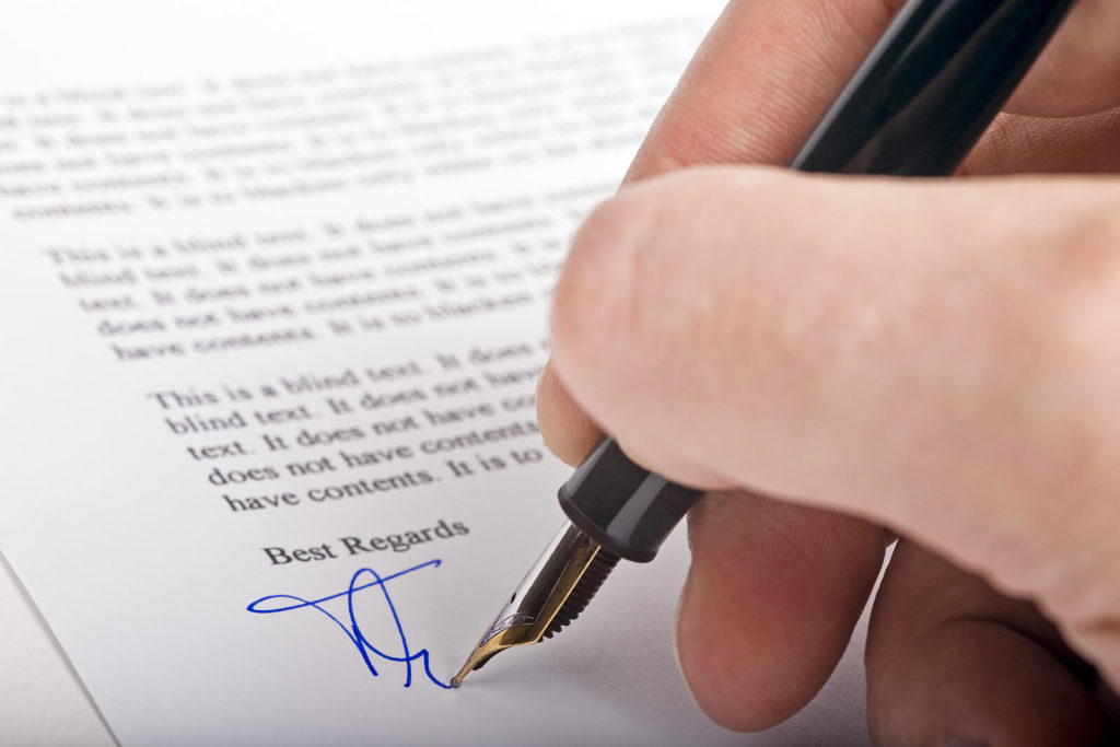 A fountain pen writing a signature with blue ink.