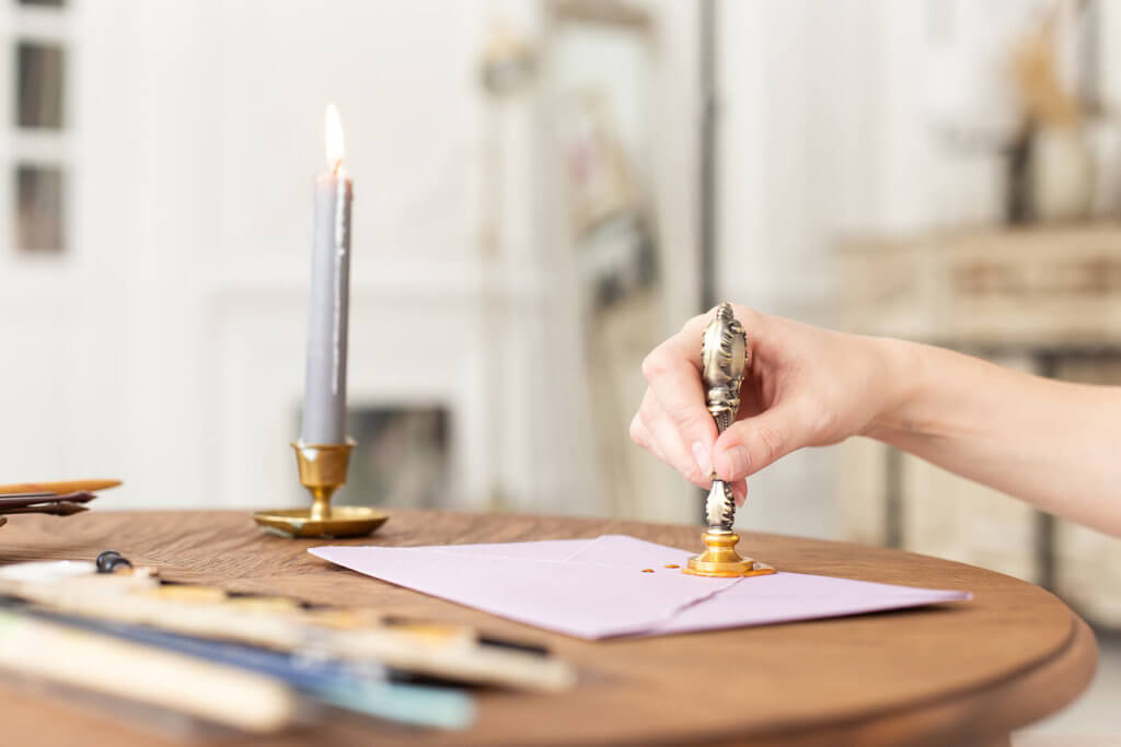 A hand stamping a wax seal on an envelope