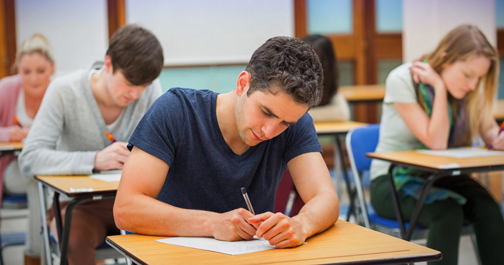 Students sitting an exam and writing with pens