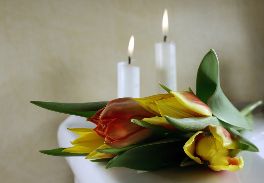 Tulips and two lit candles on a table at a funeral