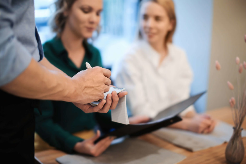 Close-up of a waiter jotting down a restaurant order from two women with an EDC pen.