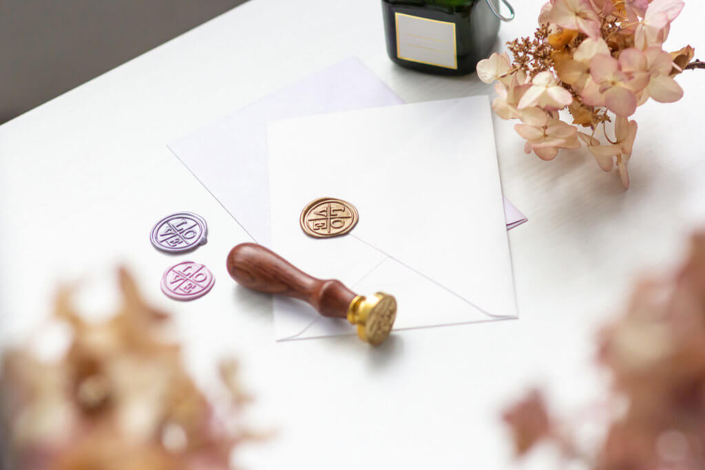 A white table with wax seals, a wax stamp and an envelope on it