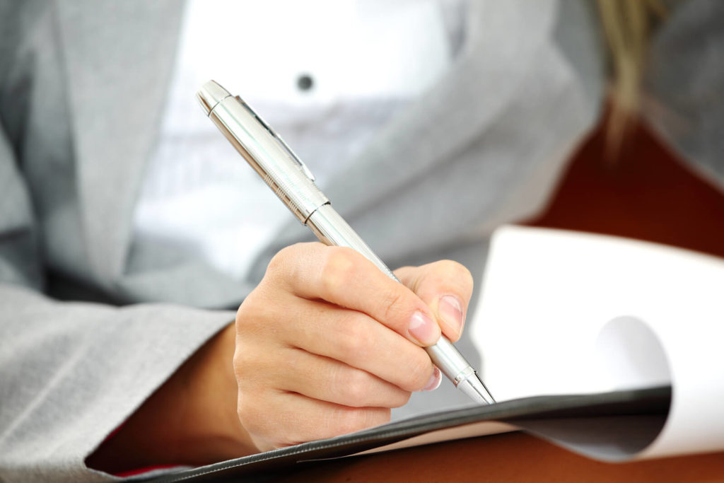 A close-up shot of a woman writing with a ballpoint pen