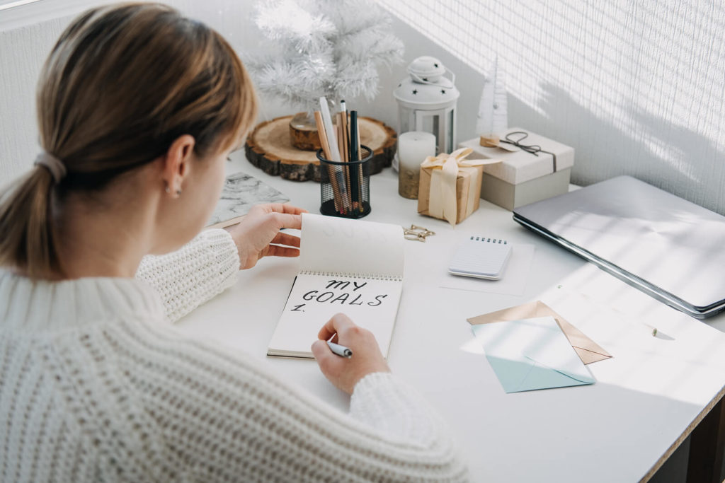 A woman sat at her desk, writing her New Year's resolutions by hand.