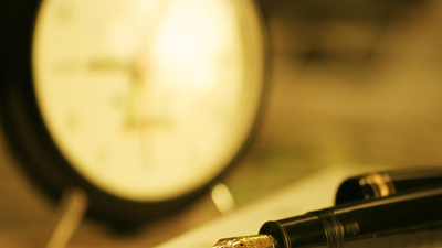 A picture of a gold-nibbed fountain pen on a page of an open notebook. The pen nib is engraved.